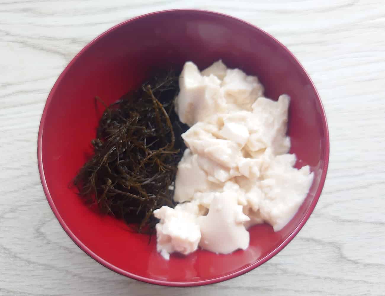 お椀に生まつもと、手で崩した豆腐1/4を入れて、味噌汁を注ぐ。